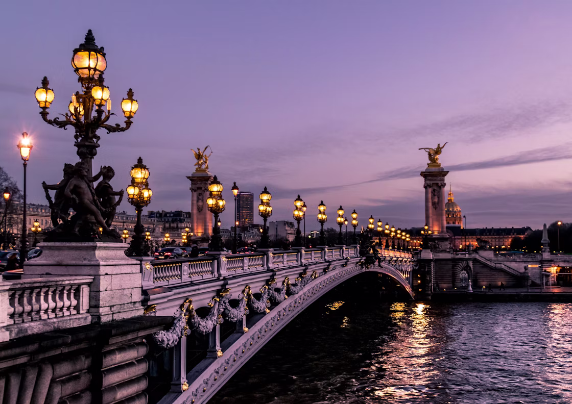 The Pont Alexandre III and its gilded lamp posts over the Seine at dusk, with the dome of Les Invalides beyond, Paris, France
