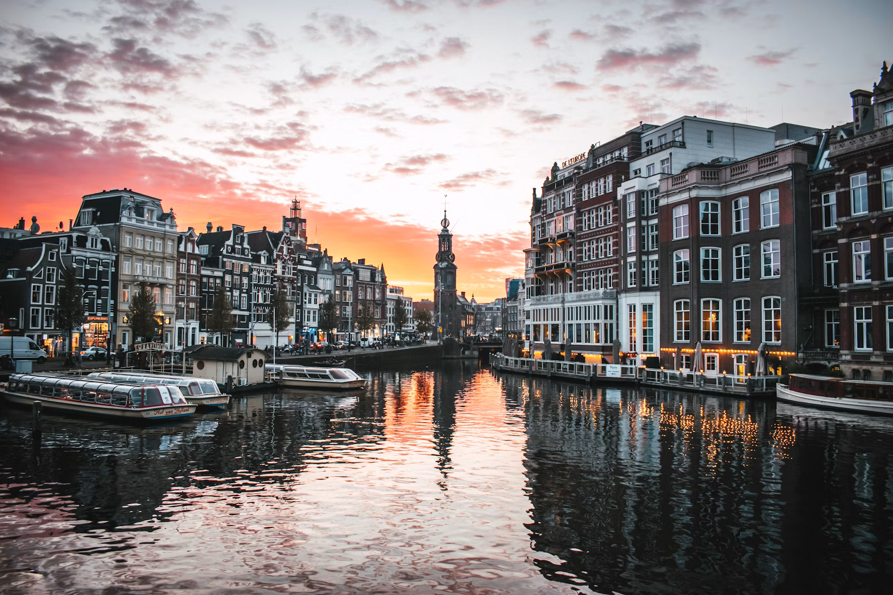 Amsterdam canal houses and the Munttoren tower reflected in the water at sunset, Netherlands