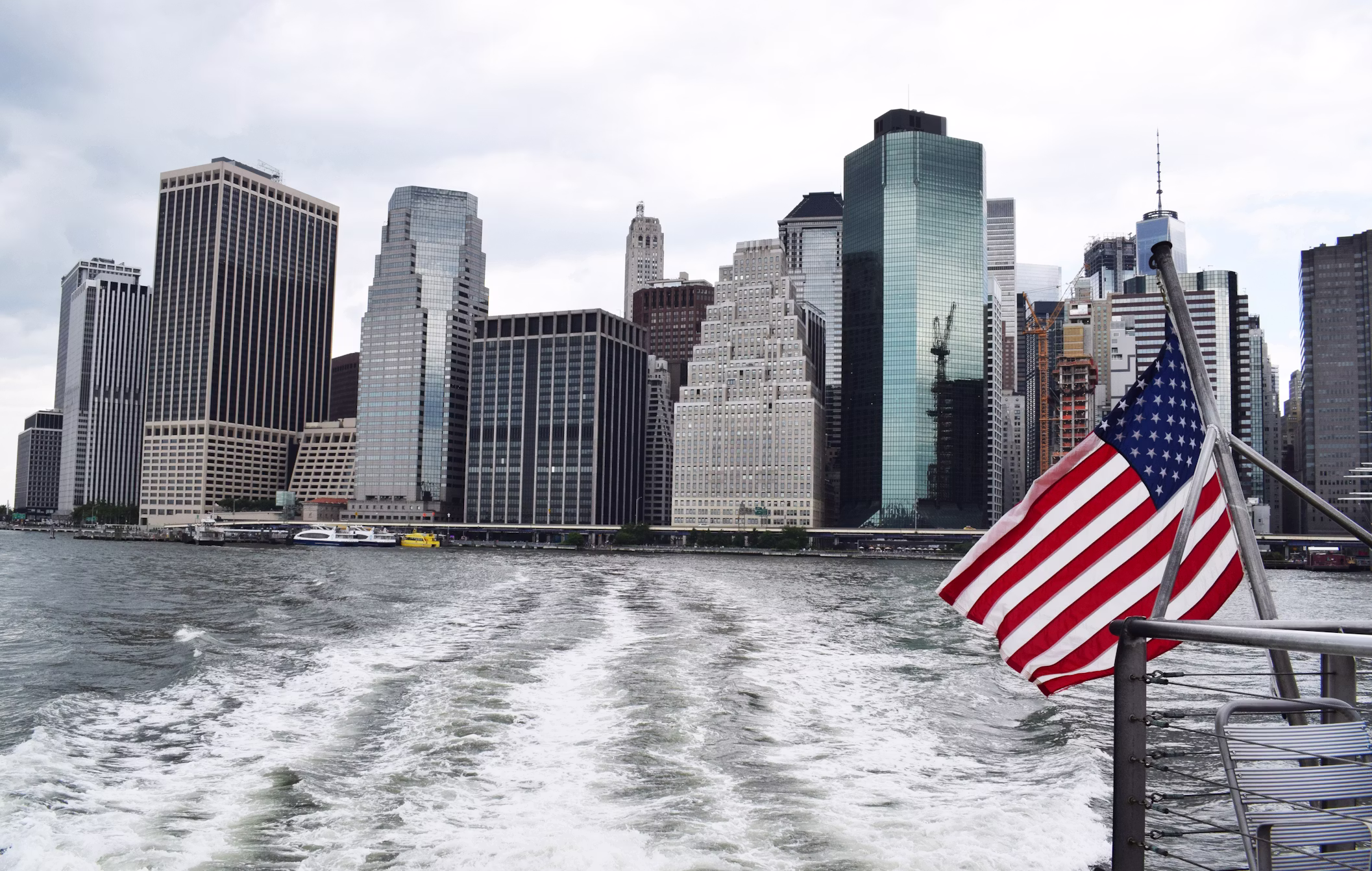 City skyline viewed from the water with an American flag on a boat