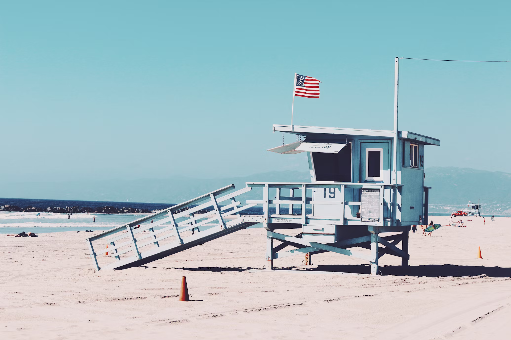 Lifeguard stand on a sunny sandy beach with American flag