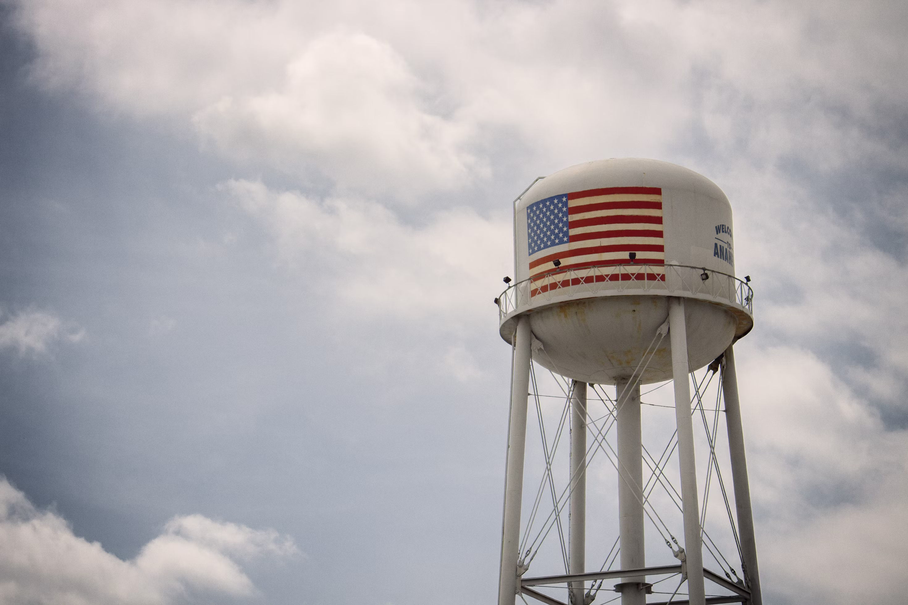 Water tower with an American flag against a cloudy sky